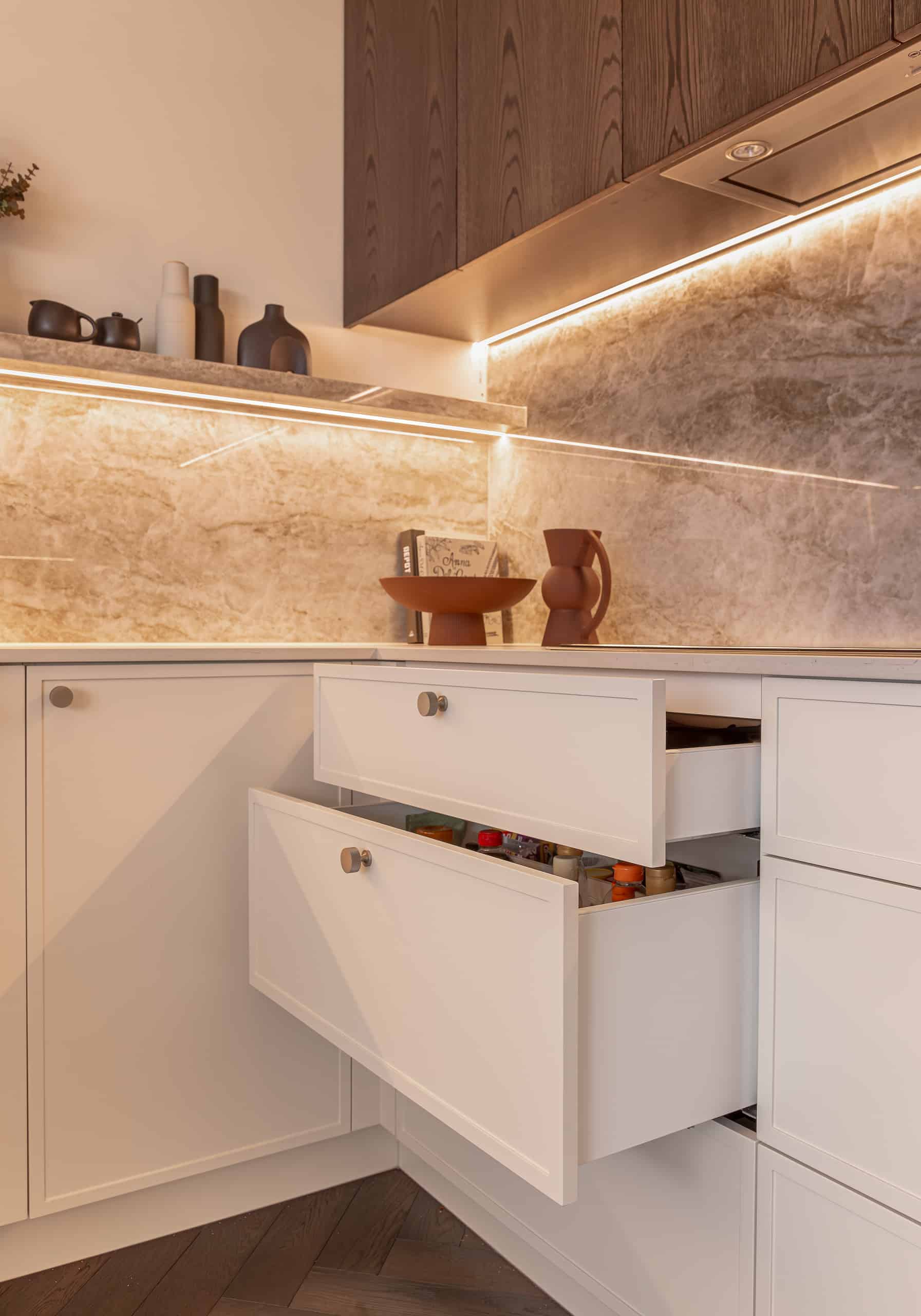 A cream kitchen with marble splashback, traditional cabinets open and brown upper cabinetry